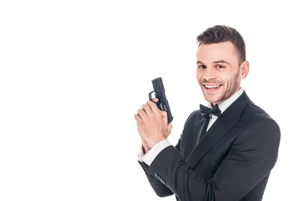Agente secreto alegre em terno preto segurando arma, isolado em branco — Fotografia de Stock