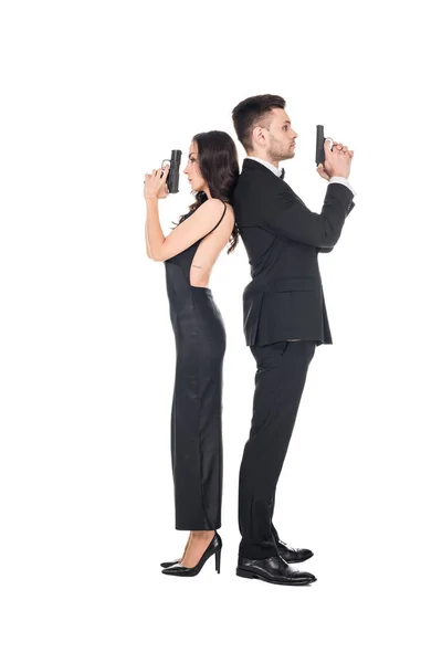 Casal de agentes secretos em roupas pretas posando com arma, isolado em branco — Fotografia de Stock