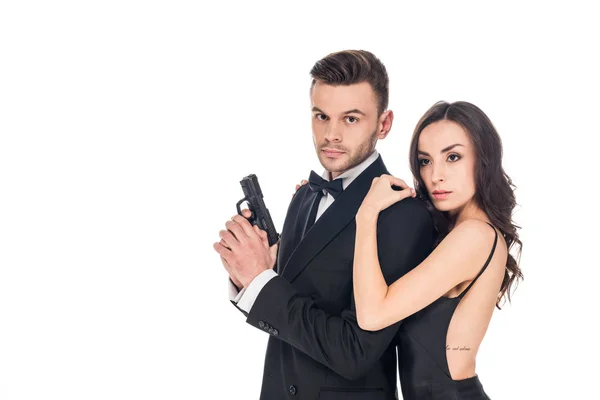 Красивая женщина обнимает мужчину секретного агента с пистолетом, изолированного на белом — стоковое фото