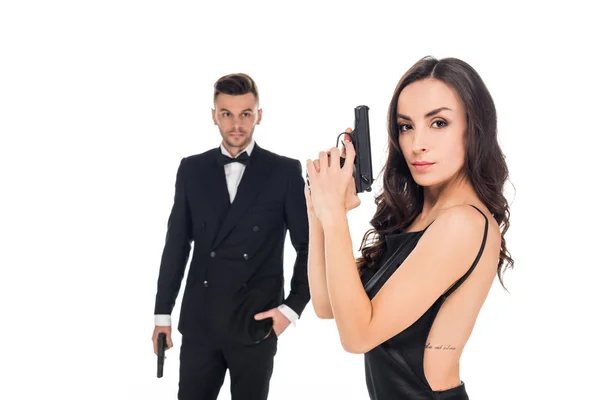 Pareja de agentes secretos vestidos de negro posando con armas, aislados en blanco - foto de stock