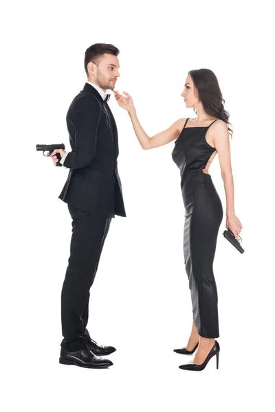 Together couple of killers in black clothes holding guns, isolated on white — Stock Photo