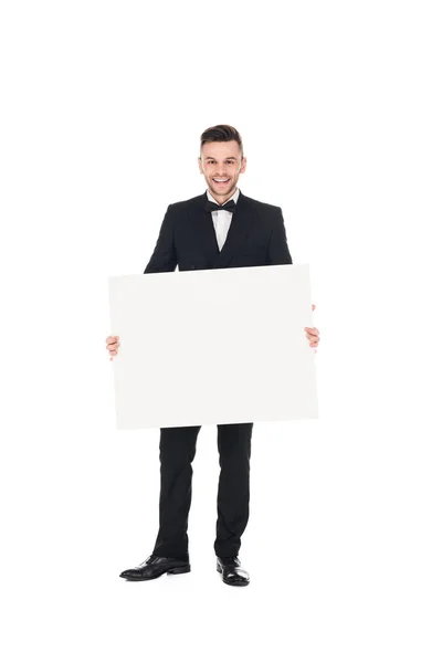 Bonito sorrindo homem elegante em terno preto posando com placa vazia isolado no branco — Fotografia de Stock