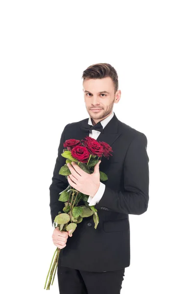 Apuesto hombre elegante en traje negro sosteniendo rosas rojas para el día de San Valentín, aislado en blanco — Stock Photo