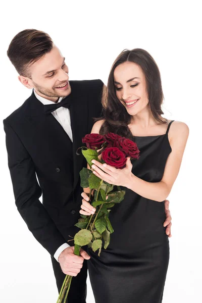 Schönes Paar posiert am Valentinstag mit roten Rosenblüten, isoliert auf weiß — Stockfoto