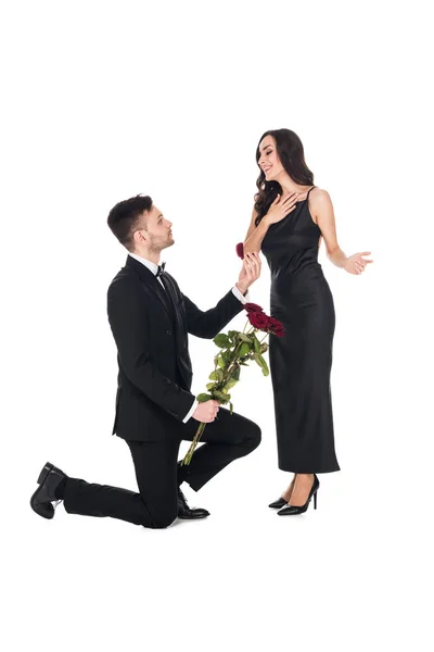 Handsome boyfriend with flowers giving proposal ring in box to surprised girlfriend, isolated on white — Stock Photo