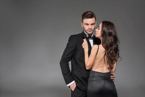 Belo casal elegante em roupas pretas abraçando isolado em cinza — Fotografia de Stock