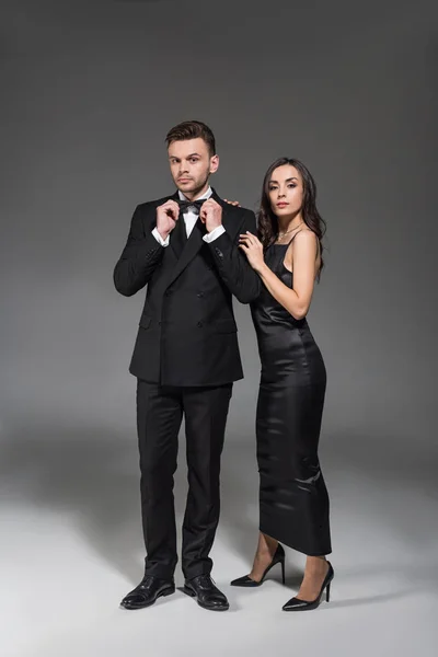 Beautiful elegant girlfriend and boyfriend in black clothes posing on grey — Stock Photo