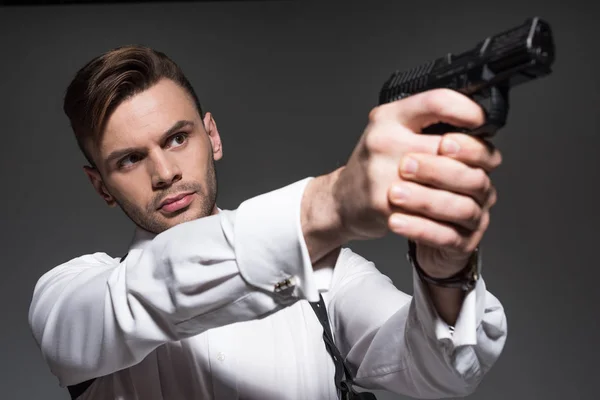 Bonito agente secreto apontando com pistola isolada em cinza — Fotografia de Stock