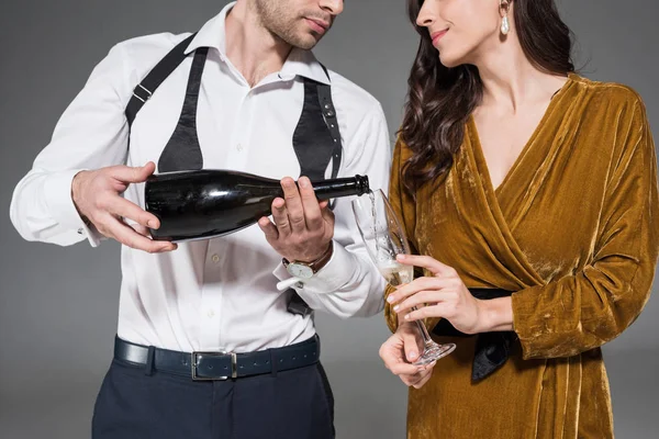 Abgeschnittene Ansicht des Freundes, der Champagner für Freundin einschenkt, isoliert auf grau — Stockfoto