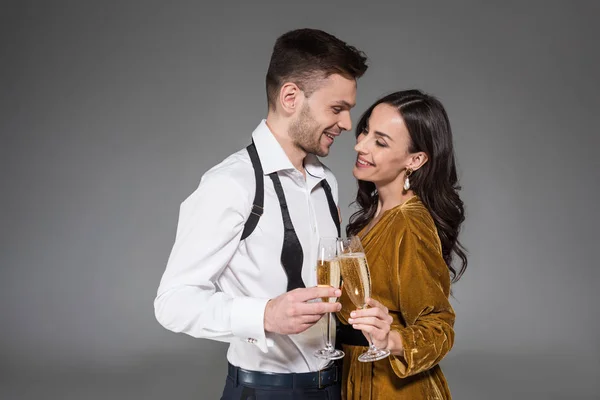 Beautiful happy couple holding champagne glasses isolated on grey — Stock Photo