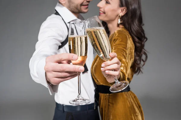 Selective focus of couple clinking with champagne glasses isolated on grey — Stock Photo