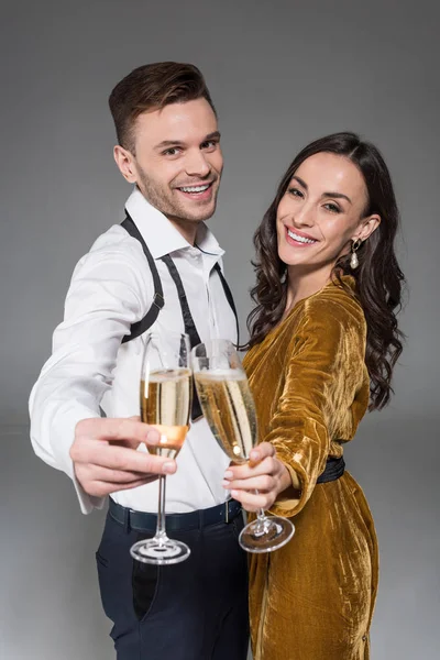 Happy couple clinking with champagne glasses isolated on grey — Stock Photo