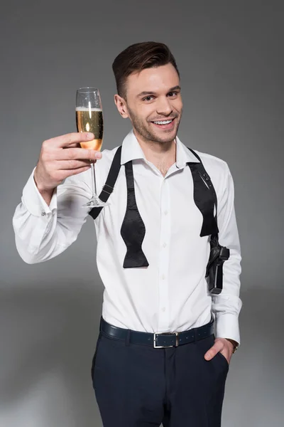 Sonriente joven brindis con copa de champán aislado en gris - foto de stock