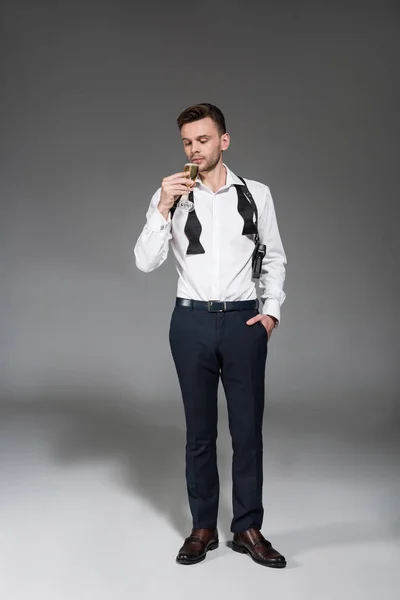 Handsome man in white shirt drinking champagne on grey — Stock Photo