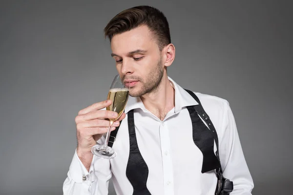 Bello giovanotto bere champagne isolato su grigio — Foto stock