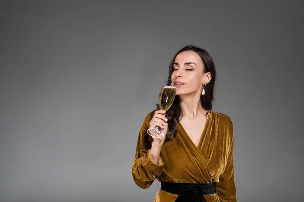 Belle femme rêveuse buvant du champagne aux yeux fermés isolé sur gris — Photo de stock