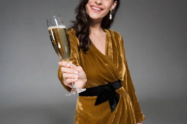 Abgeschnittene Ansicht einer lächelnden Frau mit einem Glas Champagner auf grau — Stockfoto