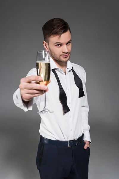 Handsome man toasting with glass of champagne isolated on grey — Stock Photo