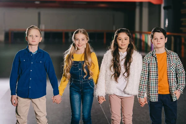 Group of pretty smiling children holding hands and looking at camera — Stock Photo