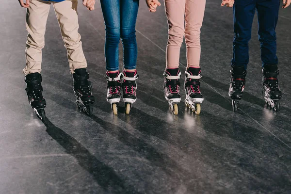 Vista parcial de crianças em patins em pé na pista de patins e de mãos dadas — Fotografia de Stock