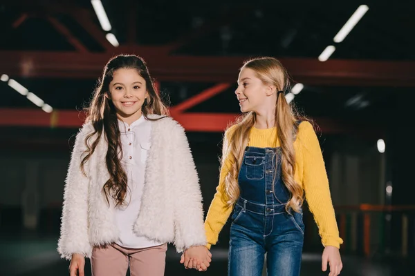 Selektiver Fokus zweier hübscher Kinder, die lächeln und Händchen halten — Stockfoto