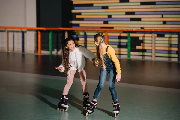 Dos amigos sonrientes de pelo largo que se preparan para empezar a moverse en patines - foto de stock