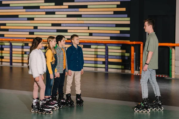 Улыбающиеся дети на роликовых коньках слушают инструкции тренеров — стоковое фото