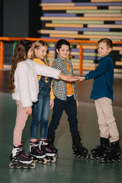 Focus sélectif de jolis enfants souriants dans des patins à roulettes étirant les mains ensemble — Photo de stock