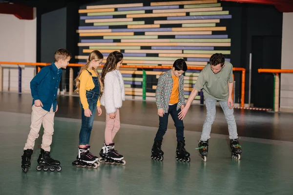 Instrucción joven explicando los métodos de patinaje a los niños - foto de stock