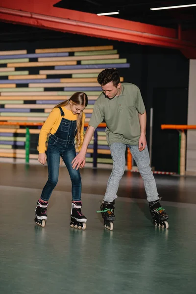 Guapo joven instructor mostrando técnicas de patinaje a niño atento — Stock Photo