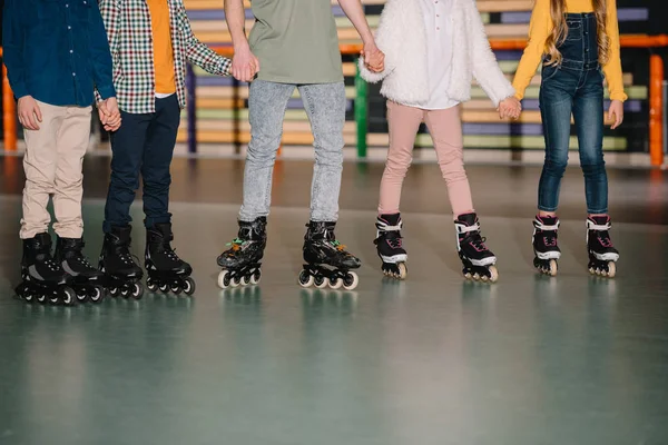 Partial view of children group in roller skates holding hands — Stock Photo