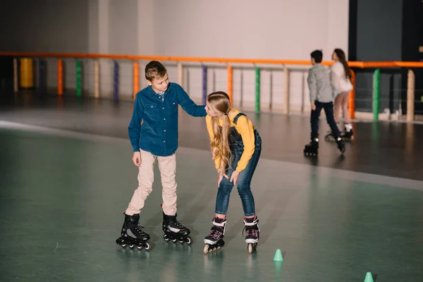 Bambini gioiosi che praticano pattinaggio su pista di pattinaggio insieme — Foto stock