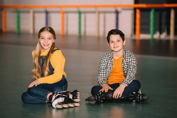 Indoor shot de niños sonrientes en patines de ruedas divirtiéndose juntos - foto de stock