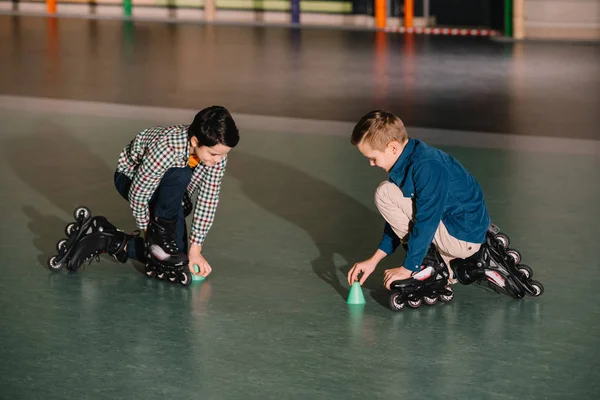 Rolo crianças em patins pretos formação em conjunto no ginásio — Fotografia de Stock