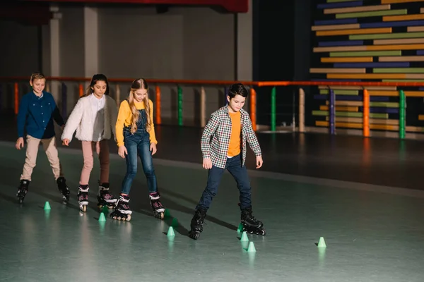 Tiro de longitud completa de los niños en patines de entrenamiento juntos - foto de stock