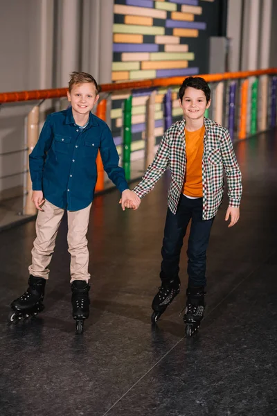 Roller boys skating together and holding hands — Stock Photo