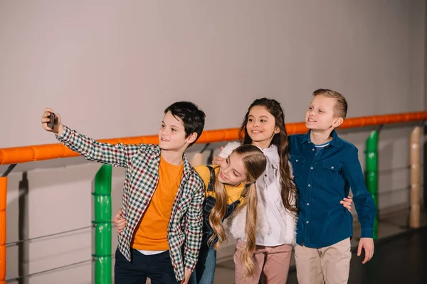 Niños emocionados abrazos y riendo mientras hacen selfie - foto de stock