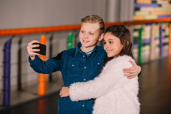 Abrazos de niño con amigo y haciendo selfie - foto de stock
