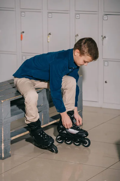 Kid in blue shirt putting on black roller skates — Stock Photo