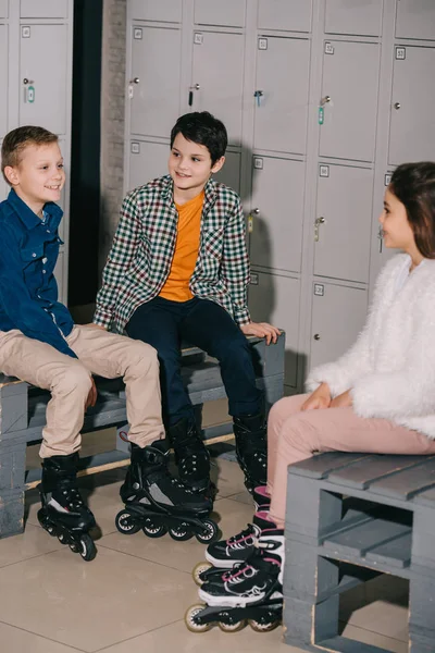 Niños sonrientes charlando después de entrenar en la pista de patinaje - foto de stock