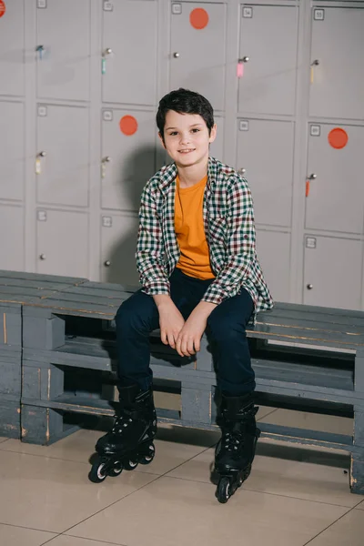 Mignon garçon brune en chemise à carreaux posant en patins à roulettes — Photo de stock