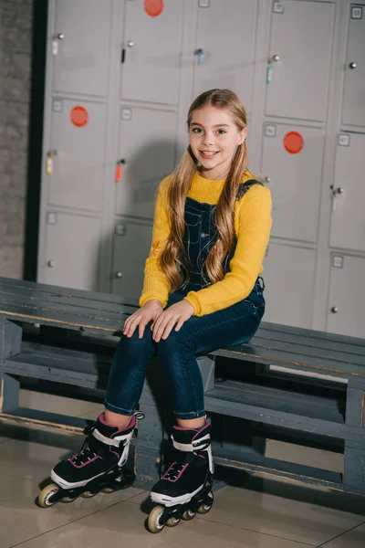 Adorable kid in yellow sweater posing in changing room with roller skates — Stock Photo