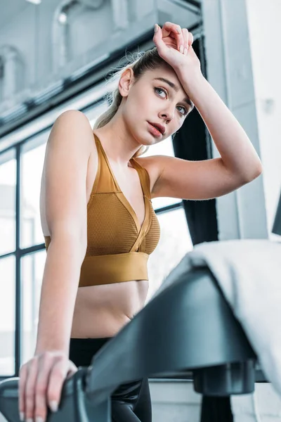 Low angle view of tired sporty girl training on treadmill in gym — Stock Photo