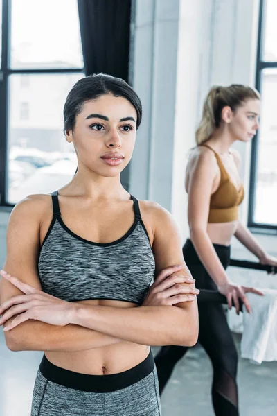 Beautiful sporty african american woman standing with crossed arms and looking away in gym — Stock Photo