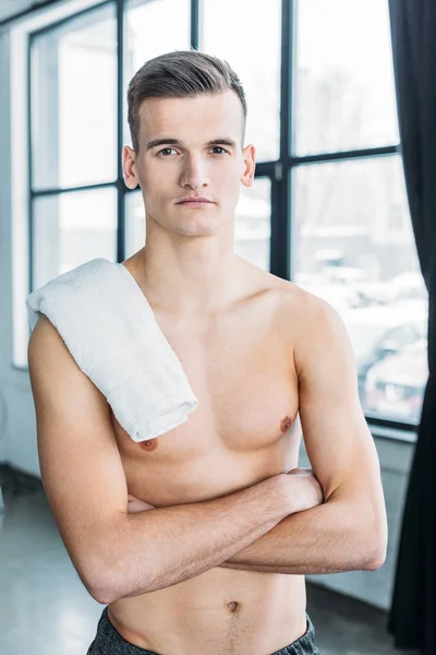 Schöner, hemdsloser Sportler, der mit verschränkten Armen in der Turnhalle steht und in die Kamera schaut — Stockfoto