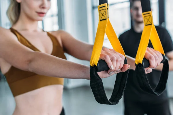 Cropped shot of young sportswoman training with suspension straps in gym — Stock Photo