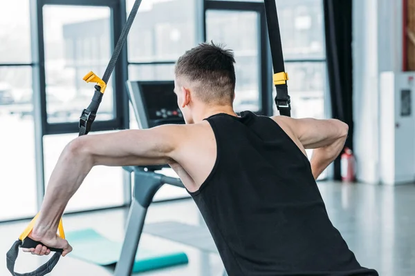 Back view of athletic young man training with resistance bands in gym — Stock Photo