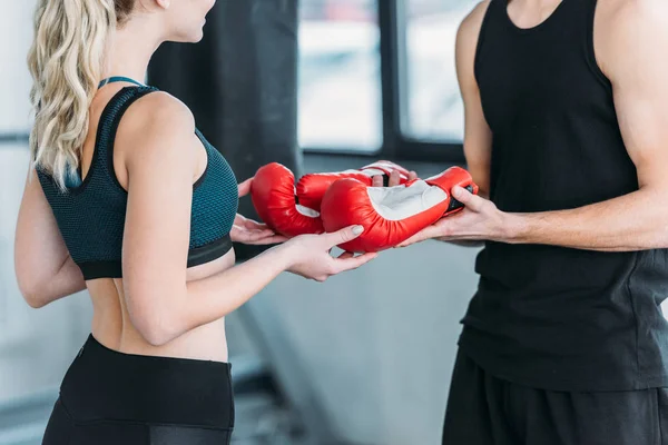 Cropped shot of young sportive man and woman holding boxing gloves in gym — Stock Photo