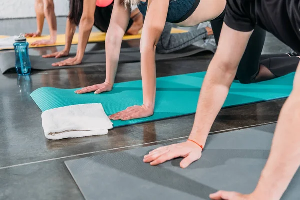 Tiro recortado de jóvenes haciendo ejercicio sobre colchonetas de yoga en el gimnasio - foto de stock