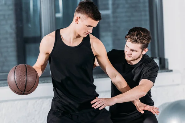 Атлетические юноши в спортивной одежде играют в баскетбол в спортзале — стоковое фото